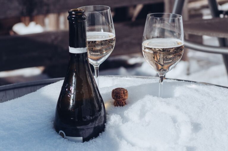 Chilled champagne bottle and glasses on a snowy table, perfect for a winter celebration.