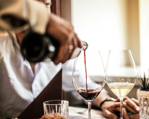 Close-up of wine being poured during an elegant romantic dinner setting with two people.